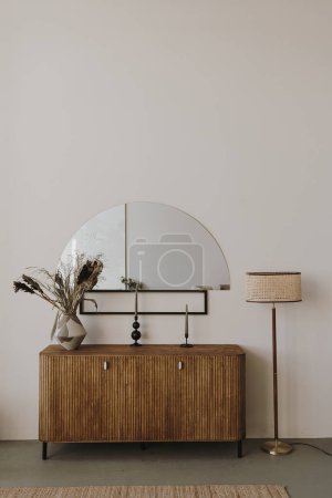 Photo for Aesthetic modern Scandinavian home interior design. Elegant bohemian living room with wooden console, mirror, floor lamp, candles, white walls, flowers bouquet, decorations - Royalty Free Image