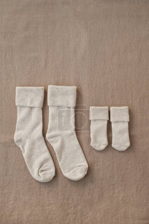 Foto de Pastel acogedor eco friendly elegante escandinavo recién nacido bebé y calcetines de la madre. Tienda de moda online, concepto de marca de compras online. Colores neutros - Imagen libre de derechos