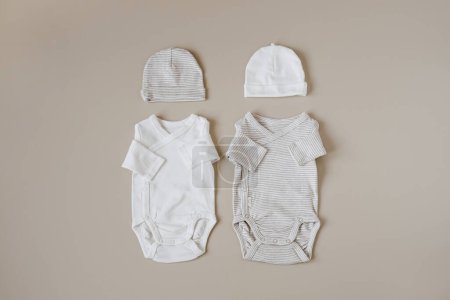 Téléchargez les photos : Cozy vêtements hygge et accessoires pour nouveau-né. Combinaisons basiques, chapeaux sur fond beige pastel. Collage esthétique minimaliste de mode bébé - en image libre de droit