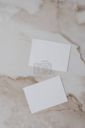 Téléchargez les photos : Flatlay de carte de papier vierge sur fond de marbre beige neutre. Modèle d'affaires. Vue de dessus, plat laïc minimaliste esthétique luxe bohème entreprise concept de marque - en image libre de droit