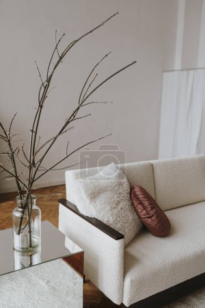 Elegantes Interieur im skandinavischen Hygge-Stil: bequemes Sofa, Kissen, weiße Wände, heimische Pflanzen. Ästhetischer Luxus helle Wohnung Innenarchitektur-Konzept
