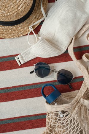 Photo for Flat lay of women's fashion accessories. Stylish female sunglasses, straw hat, shopper bag, bottle of water. Creative composition for fashion blog, web, social media. Top view - Royalty Free Image