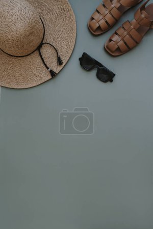 Téléchargez les photos : Composition féminine de mode d'été avec chapeau de paille, lunettes de soleil, sandales en cuir sur fond d'espace de copie pastel. Pose plate, vue sur le dessus collage minimaliste des vêtements. Blog de mode féminine, concept shopping - en image libre de droit