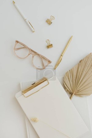 Photo for Flatlay blank copy space. Clipboard, tan fan leaf, glasses, clips on white background. Home office desk workspace. Aesthetic business, work template. Flat lay, top view - Royalty Free Image