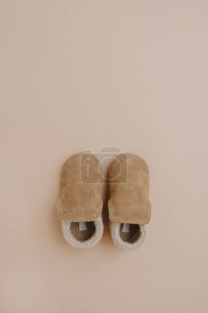 Foto de Botines cálidos de gamuza de invierno para bebé. Puesta plana de moda escandinava nórdica para niños. Color beige pastel neutro estético - Imagen libre de derechos
