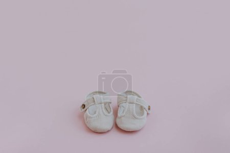 Téléchargez les photos : Paire de mini chaussures pour enfants sur fond rose pastel neutre. Couché plat, vue sur le dessus vêtements de bébé scandinave élégant - en image libre de droit