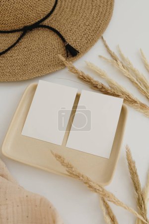 Photo for Pampas grass stems, straw hat, muslin fabric, beige plate. Paper card sheets with empty clipping path copy space - Royalty Free Image