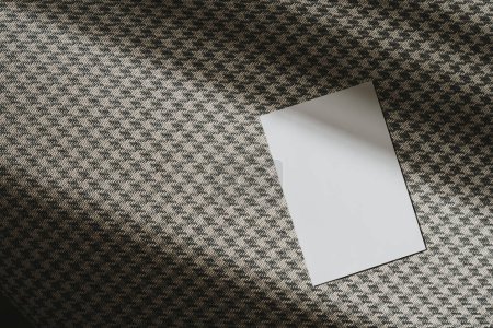 Foto de Tarjetas de hoja de papel en blanco con espacio de copia de maqueta, sombra de luz solar sobre fondo de patrón de tela clásico sin costuras - Imagen libre de derechos