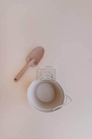 Foto de Cubo de silicona de juguete y pala para que el bebé juegue con agua y arena. Colocación plana, vista superior fondo rosa claro - Imagen libre de derechos