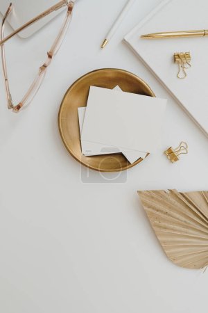 Photo for Blank paper sheet card with mockup copy space, dry fan leaf, gold stationery on white background. Flat lay, top view aesthetic minimal business brand template - Royalty Free Image