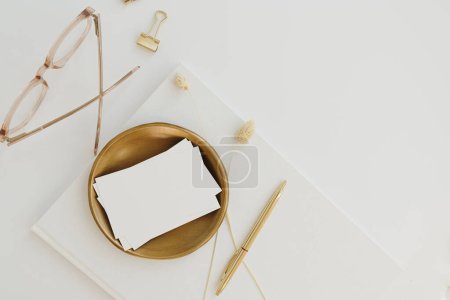 Photo for Blank paper sheet card with mockup copy space on white background. Aesthetic bohemian minimal business brand template. Home office desk workspace with gold stationery. Flat lay, top view - Royalty Free Image