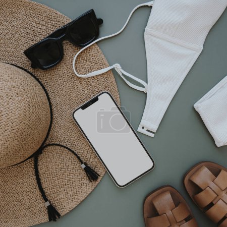 Photo for Flatlay of aesthetic women's fashion accessories. Mobile phone with blank copy space screen. Stylish female straw hat, swimsuit, sunglasses, sandals on pastel background. Top view, flat lay - Royalty Free Image