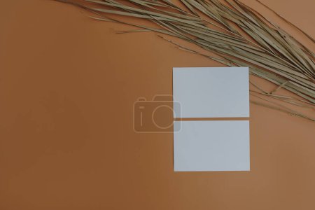Photo for Blank paper sheet card with mockup copy space, dried palm leaf stem on orange background. Aesthetic bohemian minimal business brand template. Flat lay, top view - Royalty Free Image