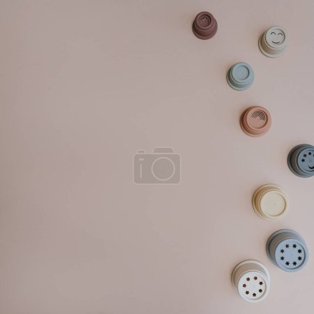 Photo for Modern Scandinavian nordic style baby toys on pastel pink background. Set of stacking tower cups in neutral pastel colors. Baby toys for playing with sand. Flat lay, top view - Royalty Free Image