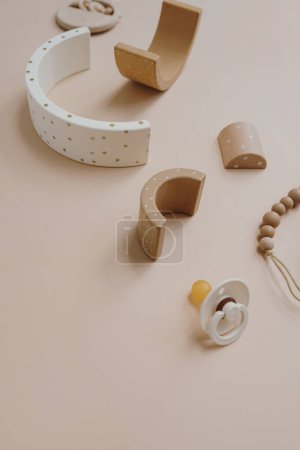 Photo for Rainbow stacking toy, pacifier, pacifier holder on soft color background. Pastel beige cute stylish Scandinavian children's baby toys and accessories. Online fashion store, shopping concept - Royalty Free Image
