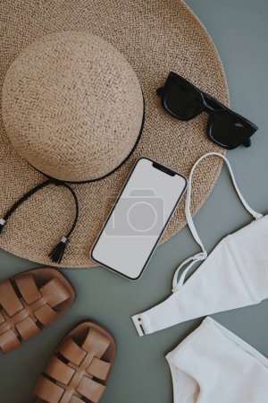 Photo for Feminine summer fashion composition with straw hat, sunglasses, sandals on pastel background. Smartphone with copy space screen. Flat lay, top view clothes. Female fashion blog, shopping concept - Royalty Free Image