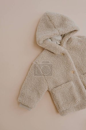 Téléchargez les photos : Manteau d'hiver chaud pour bébé enfant. Pose plate de vêtements scandinaves nordiques pour enfants. Couleur beige pastel neutre esthétique - en image libre de droit