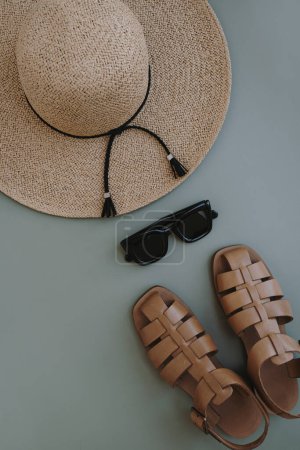 Foto de Pisos de accesorios estéticos de moda femenina. Elegantes gafas de sol femeninas, sombrero de paja, sandalias sobre fondo azul pastel. Vista superior, plano - Imagen libre de derechos