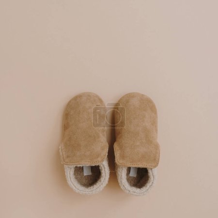 Téléchargez les photos : Chaussons chauds en daim d'hiver pour bébé enfant. Pose plate de vêtements scandinaves nordiques pour enfants. Couleur beige pastel neutre esthétique - en image libre de droit