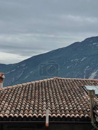 Photo for Rustic Italian architecture. Traditional historic European country building with shingles tile roof in front of mountains. Aesthetic summer vacation travel concept - Royalty Free Image
