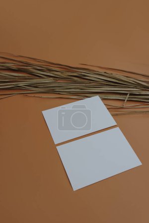 Foto de Hoja de tarjeta de papel con espacio de copia maqueta en blanco, hoja de palma seca sobre fondo naranja. Plantilla de espacio de copia maqueta arriba - Imagen libre de derechos