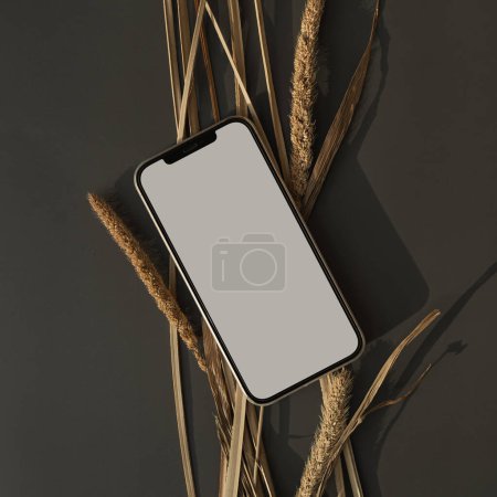 Photo for Flatlay mobile phone on dark table. Aesthetic elegant blog, online shopping, online store, social media branding template with blank copy space. Dried grass stems - Royalty Free Image