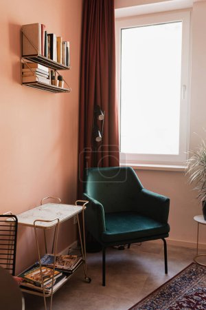 Photo for Aesthetic modern Scandinavian home interior design. Elegant bohemian living room with coral walls, comfortable lounge chair, carpet, coral color walls, marble table, decorations - Royalty Free Image