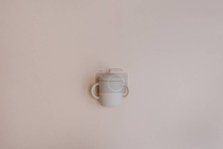 Photo for Silicone mug for little baby kid to drink on light pastel pink background. Flat lay, top view - Royalty Free Image