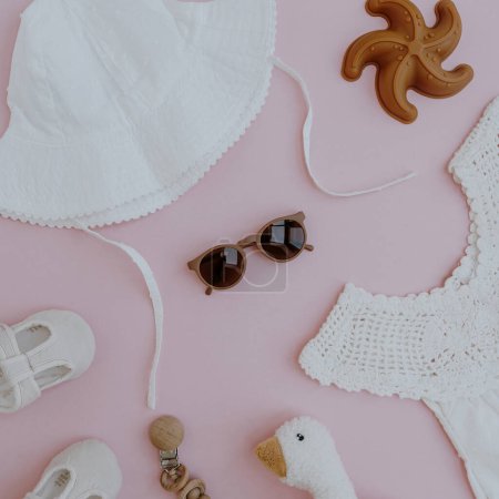 Téléchargez les photos : Ensemble de vêtements d'été mignons et accessoires pour bébé fille sur fond rose. Couché plat, vue de dessus de la collection de mode élégante pour petit bébé - en image libre de droit