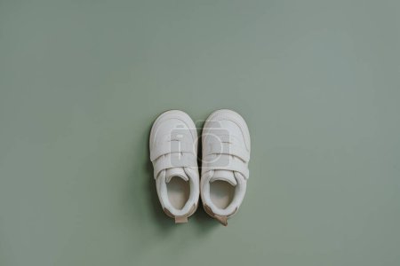 Photo for White mini sneaker shoes. Baby shoes on soft pastel green background. Fashion Scandinavian children's clothes. Flat lay, top view - Royalty Free Image