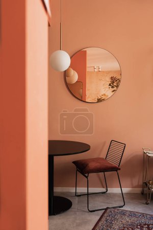 Photo for Aesthetic elegant home living room interior with coral walls, comfortable chair, mirror, table, carpet, mirror. Scandinavian interior design - Royalty Free Image