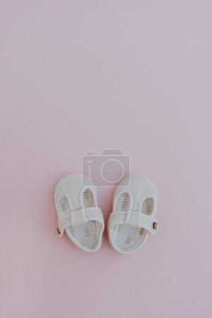 Foto de Mini sandalias para niños recién nacidos. Zapatos de bebé sobre fondo rosa pastel. Moda Ropa infantil escandinava. Piso tendido, vista superior - Imagen libre de derechos
