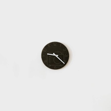 Foto de Reloj negro en pared blanca. Minimalista decoración de interiores del hogar. Concepto de tiempo - Imagen libre de derechos