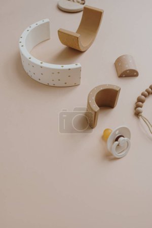 Téléchargez les photos : Élégant collage d'accessoires pour bébés et jouets pour enfants sur fond beige neutre de couleur douce. Tétine, jouet empilable arc-en-ciel, porte-sucette - en image libre de droit