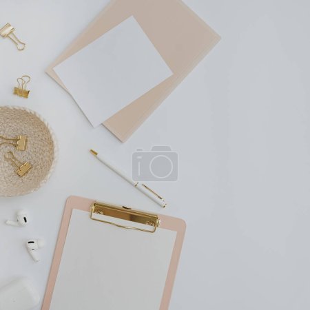 Photo for Clipboard, headphones, elegant women's accessories on white background with blank mockup copy space. Flat lay, top view minimalist home office desk workspace template - Royalty Free Image