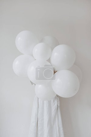 Foto de Mujer en vestido blanco sosteniendo racimo de globos de cumpleaños sobre fondo blanco. Fiesta festiva fiesta fiesta concepto de celebración. Tiempo de fiesta - Imagen libre de derechos
