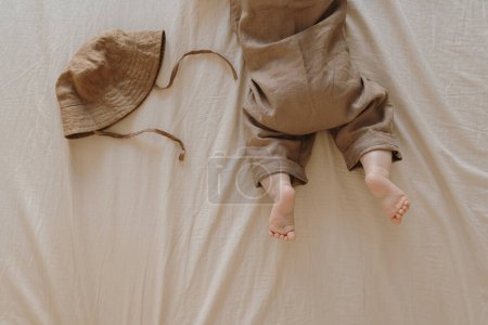 Photo for Flatlay newborn baby in cute brown bodysuit lying on bed linens - Royalty Free Image