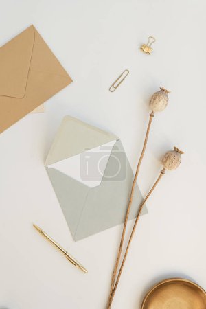 Photo for Holiday, anniversary celebration, party event invitation preparation concept. Invitation cards, craft envelopes, poppy stems, pen on white background. Flat lay, top view - Royalty Free Image