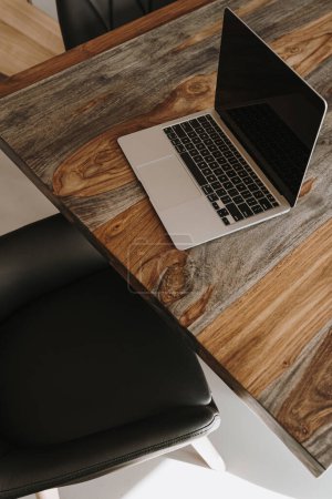 Téléchargez les photos : Bureau à domicile espace de travail avec ordinateur portable, table en bois massif, chaise en cuir. Concept de design d'intérieur moderne - en image libre de droit