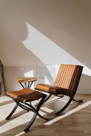 Foto de Estética lujosa casa moderna interior decorado con sillón de cuero de color naranja y mesa de centro. Sombras de luz solar en la pared. Espacio de descanso para relajarse y relajarse - Imagen libre de derechos