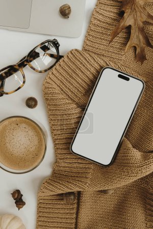 Photo for Aesthetic autumn, fall styled online store, blog, social media branding composition. Mobile phone with blank copy space screen, coffee, glasses, knitted cloth. Neutral colours template - Royalty Free Image