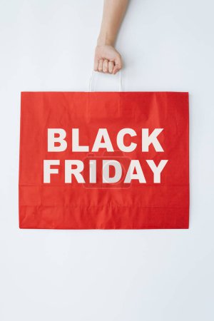 Photo for Hand holding red craft shopping bag with sign BLACK FRIDAY. Minimal Black Friday shopping, sale, promotion concept - Royalty Free Image