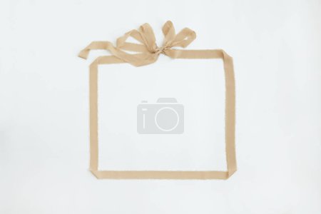 Téléchargez les photos : Cadre de ruban beige avec noeud sur fond blanc. Modèle de carte de vacances. Modèle de maquette d'espace de copie vierge - en image libre de droit