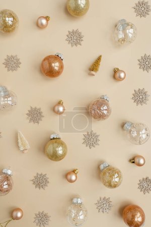 Foto de Confiti dorado y pelotas de juguete navideñas sobre fondo beige neutro. Piso laico, vista superior Navidad vacaciones fondo - Imagen libre de derechos