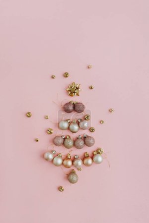 Foto de Vista superior de bolas de bolas y decoraciones arregladas en árbol de Navidad con juguetes sobre fondo rosa - Imagen libre de derechos