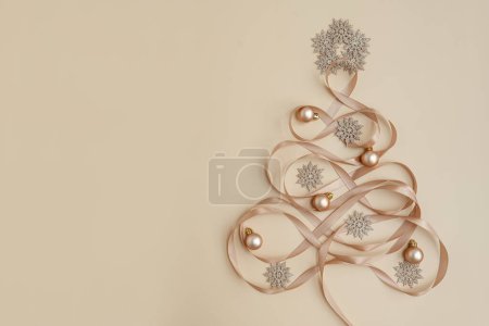 Téléchargez les photos : Sapin de Noël créatif fait de décorations de vacances sur fond beige neutre. Carte de voeux du Nouvel An. Couché plat, vue du dessus - en image libre de droit