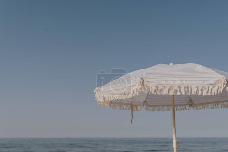 Foto de Mínimo concepto de vacaciones de verano. Sombrilla de playa frente al cielo azul y el mar. Relajante, descansando en la playa - Imagen libre de derechos