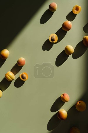 Téléchargez les photos : Modèle de fruits de pêches fraîches avec des ombres de lumière du soleil sur fond vert pastel neutre - en image libre de droit