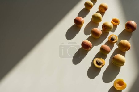 Téléchargez les photos : Composition plate avec des pêches mûres sur fond beige neutre avec des ombres de lumière du soleil - en image libre de droit
