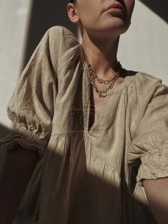 Foto de Mujer bonita joven en vestido de lino y contra la pared. Silueta a la luz del sol. Sombras en la pared. Concepto de diseño de moda mínimo. Estética - Imagen libre de derechos